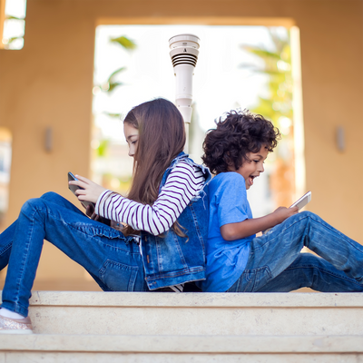 2 children looking at a smart tablet with in the background a Tempest weather device on a pole