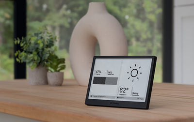 Smart TRMNL display device on a wooden surface with weekly progress and weather 