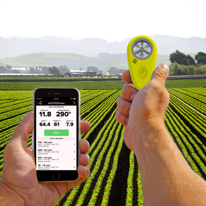 A hand holding the Tempest WEATHERmeter for Agriculture  and monitoring it on the WEATHERmeter app in front of a field