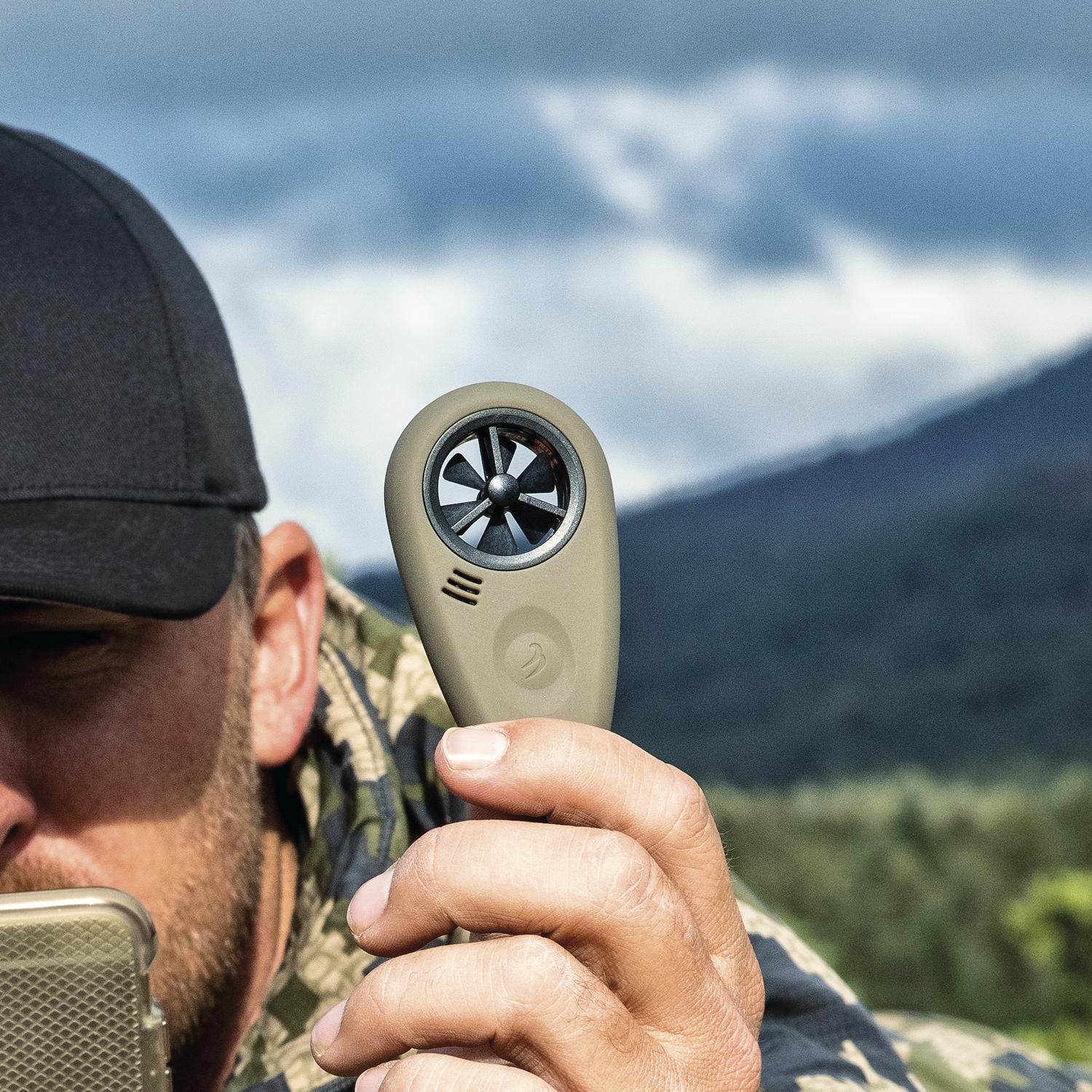 A man holding the Tempest WEATHERmeter for Precision Shooting in flat dark earth